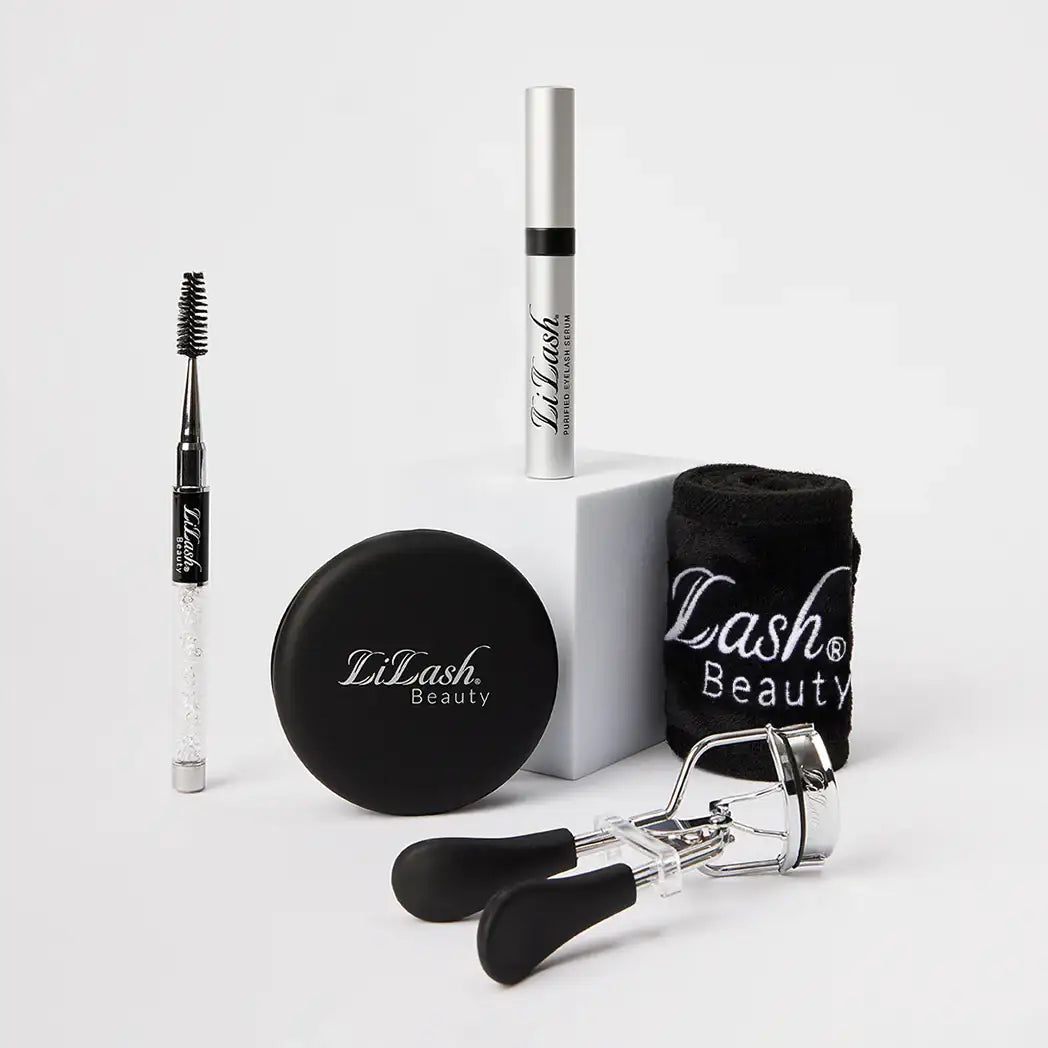 LiLash Beauty eyelash serum, eyelash curler, brow brush, compact mirror, and branded black towel on white background