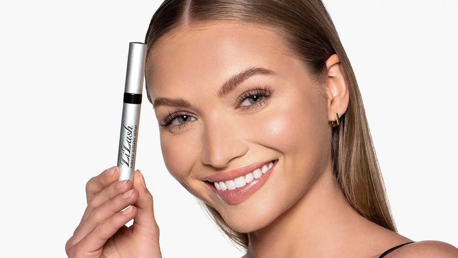 Smiling woman holding LiLash purfied eyelash serum tube showcasing longer, fuller lashes and defined brows
