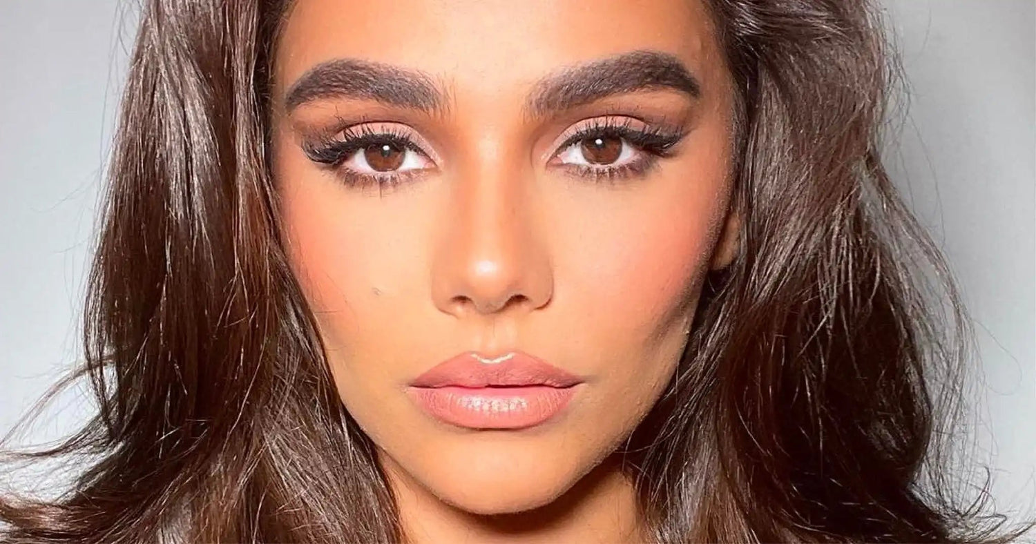 Close-up of a woman with long lashes, defined brows, and glowing skin showcasing LiLash Beauty makeup