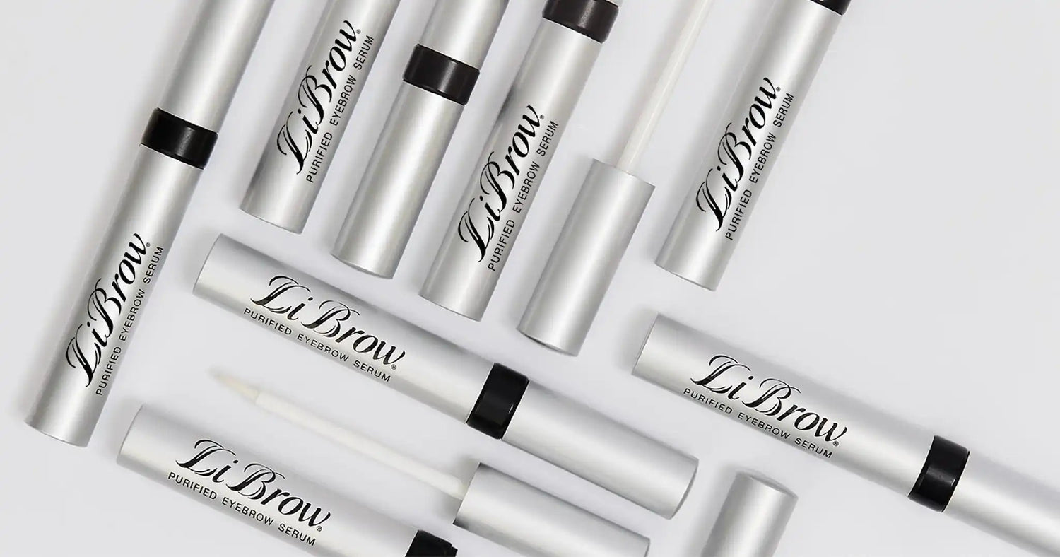 Multiple silver tubes of LiBrow Purified Eyebrow Serum arranged on a white surface with some open showing applicator
