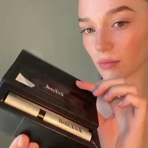 Woman holding eyelash serum with sleek packaging for longer, fuller lashes