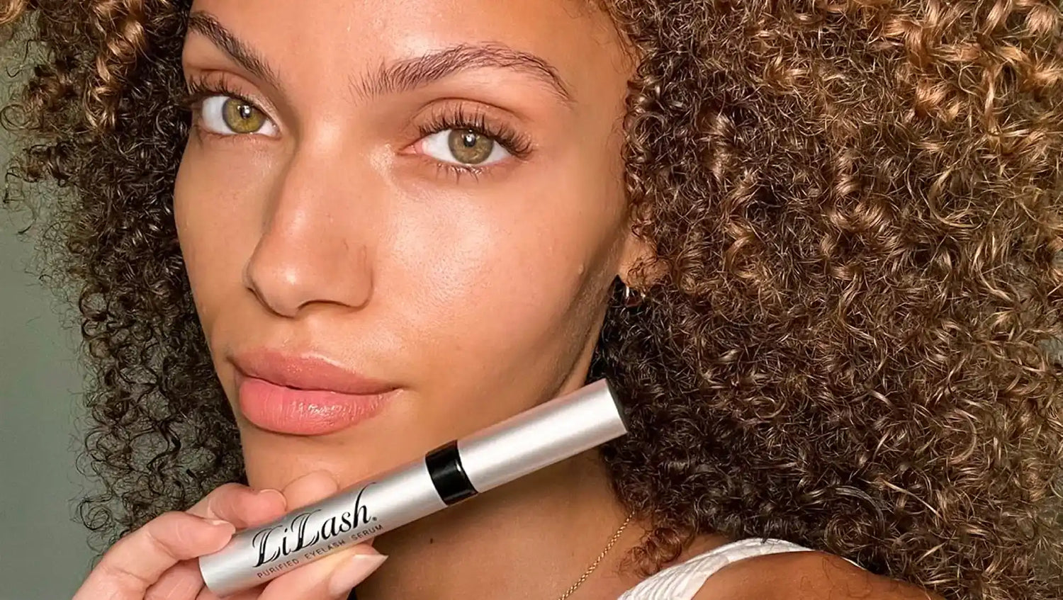 Woman holding LiLash eyelash serum for longer, fuller lashes with defined brows