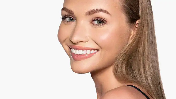 Woman with long, full lashes and defined brows smiling brightly