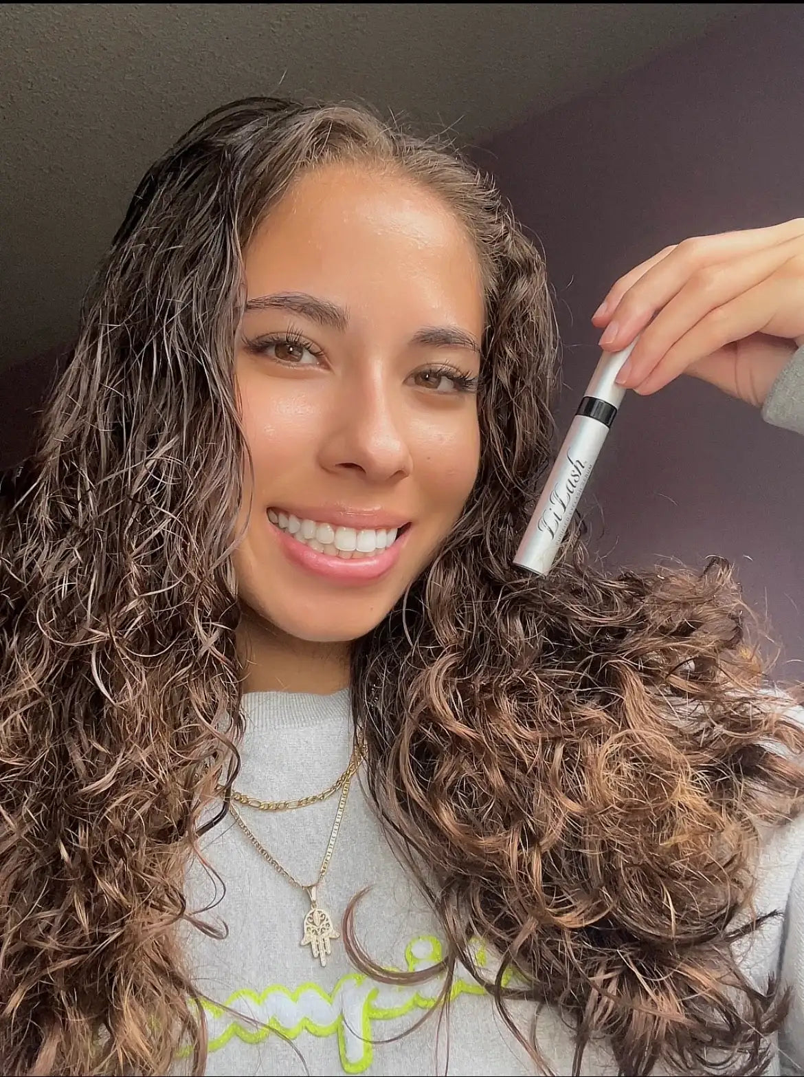 Woman holding LiLash lash serum for longer, fuller lashes with radiant smile