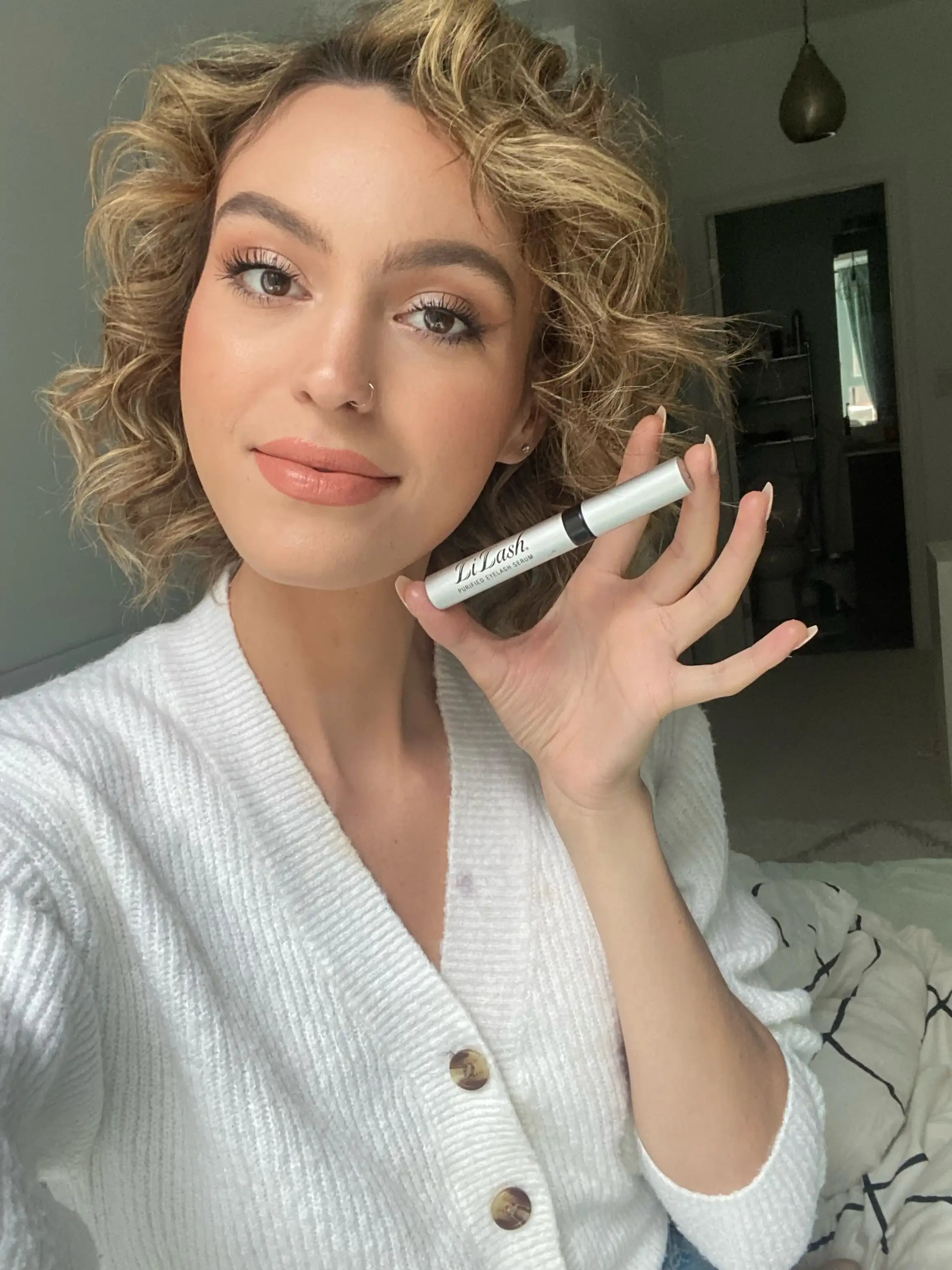 Woman holding eyelash serum for longer, fuller lashes with natural beauty look
