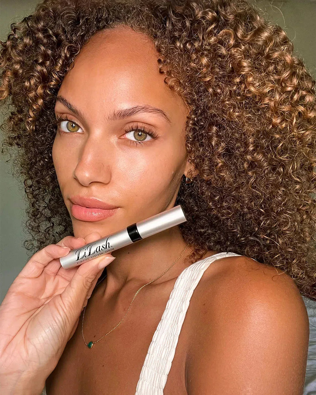 Woman holding LiLash eyelash serum for longer, fuller lashes and defined brows