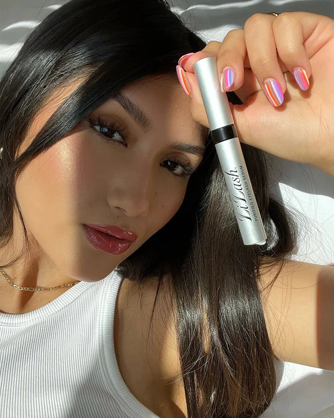 Woman holding eyelash serum for longer, fuller lashes with defined brows