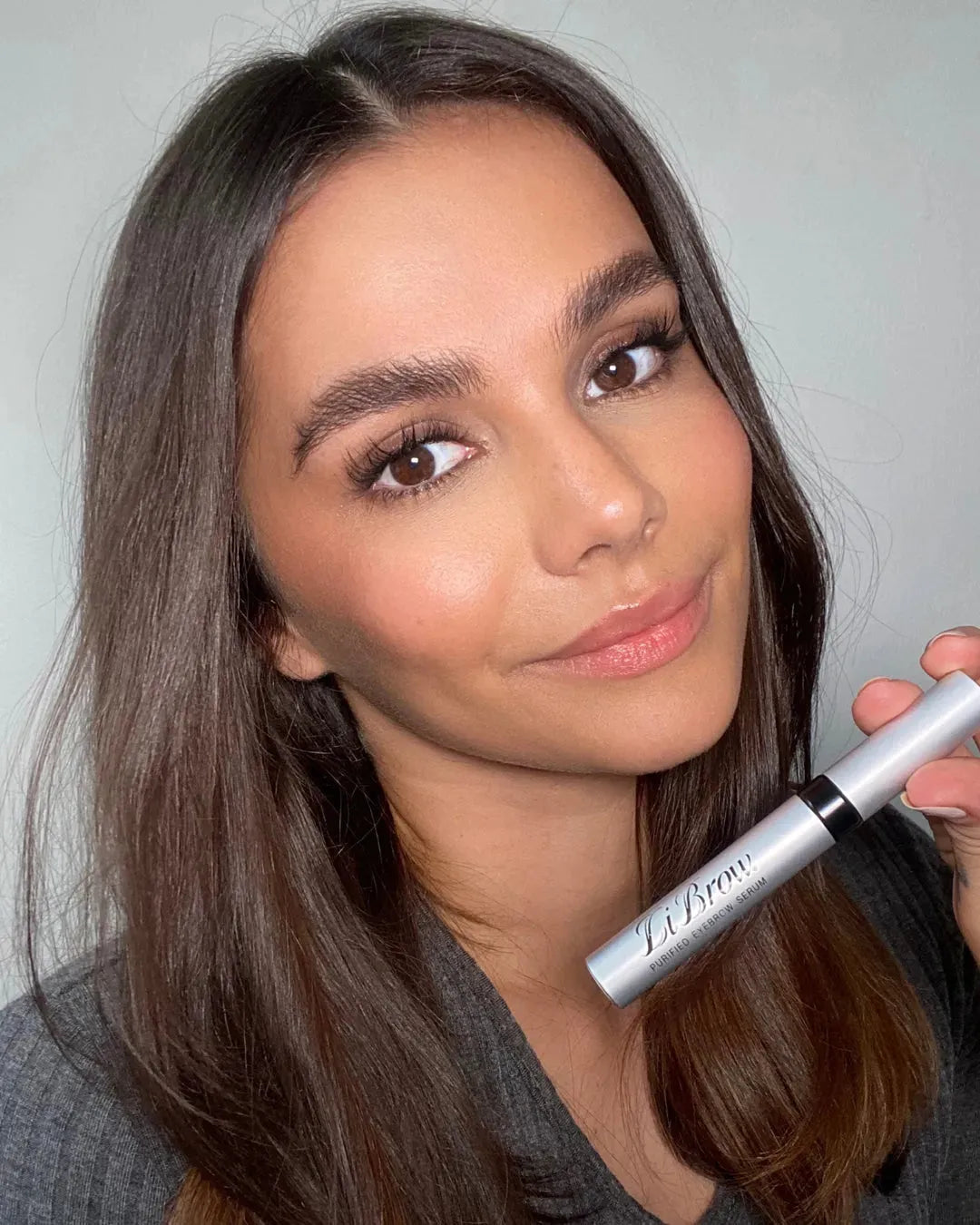 Woman holding LiBrow purified eyebrow serum for fuller, defined brows