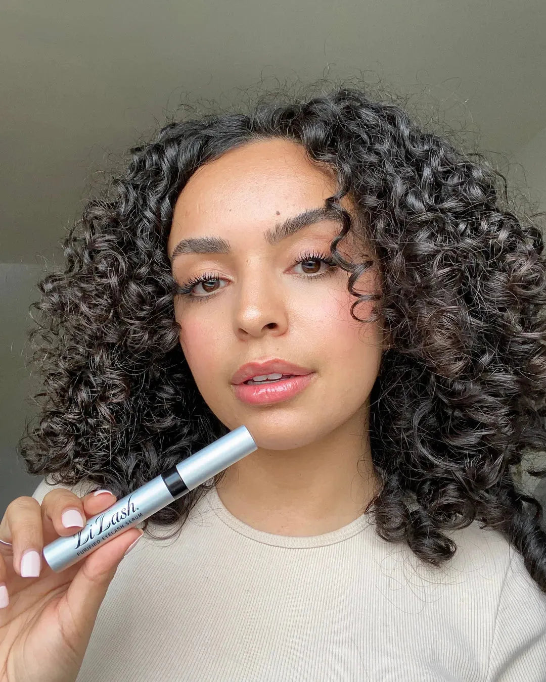 Woman holding LiLash eyelash serum for longer, fuller lashes with defined brows