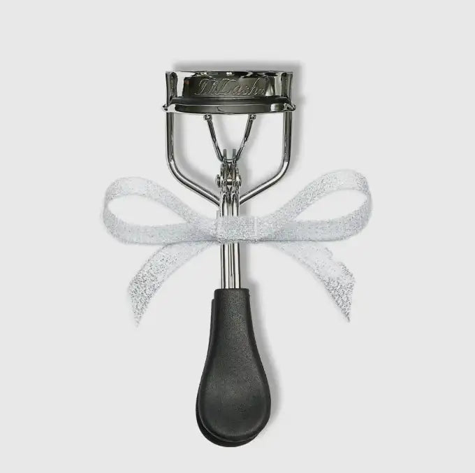 Silver eyelash curler with a white glittery ribbon bow tied around the center.