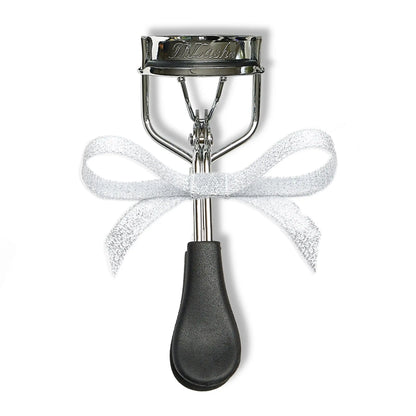 Metal eyelash curler with black handle and white bow on white background
