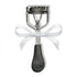 Metal eyelash curler with black handle and white bow on white background