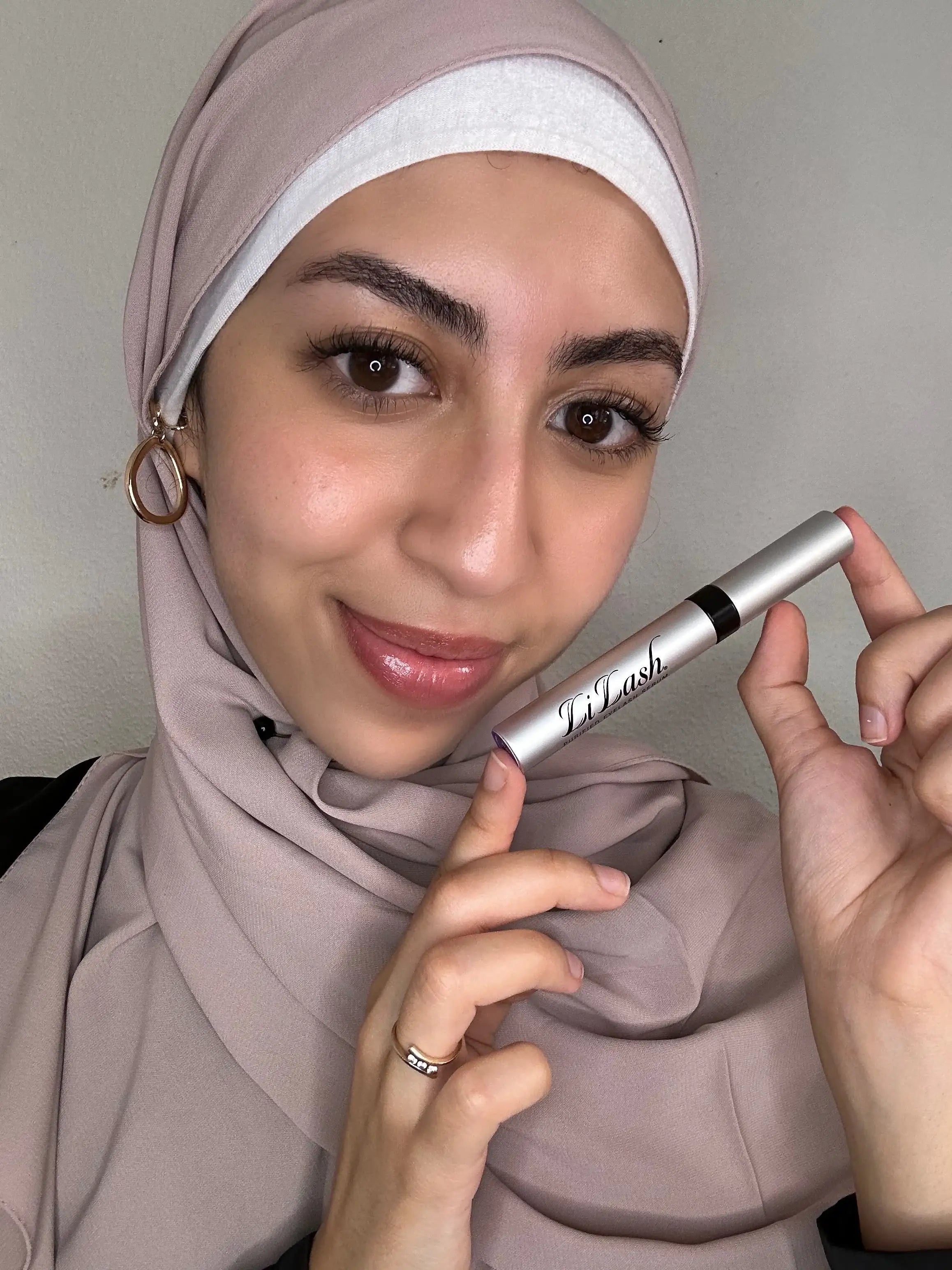 Woman holding LiLash lash serum, showcasing fuller lashes and defined brows
