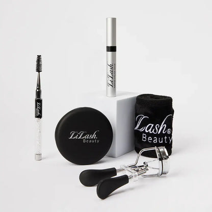 LiLash Beauty eyelash serum, eyelash curler, brow brush, compact mirror, and branded black towel on white background