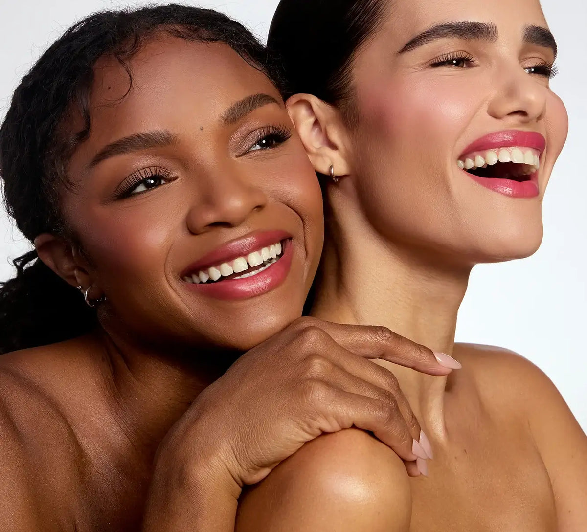 Two smiling women with radiant skin, defined brows, and long lashes.