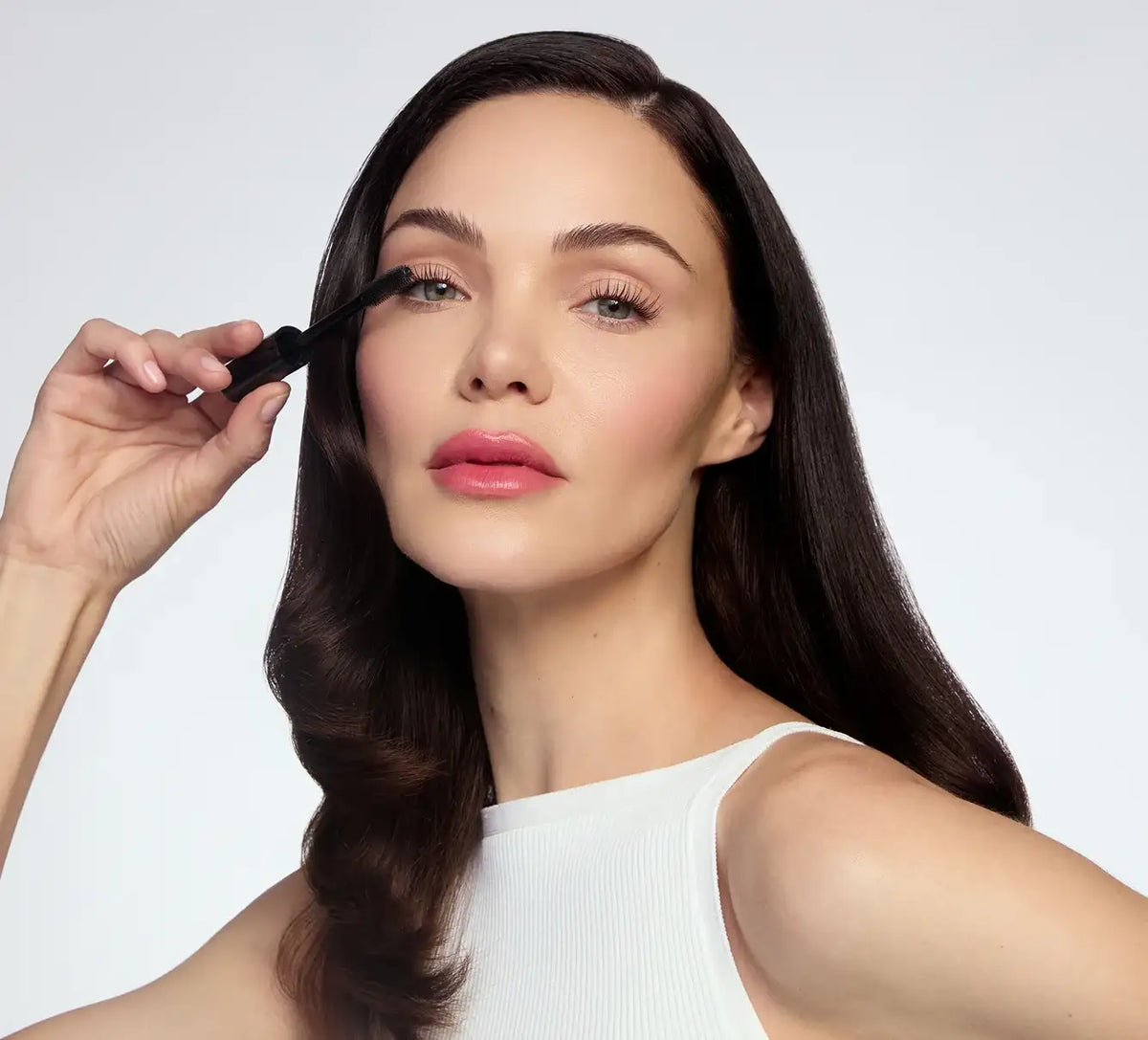 Woman applying mascara to her eyelashes for a longer, fuller look.